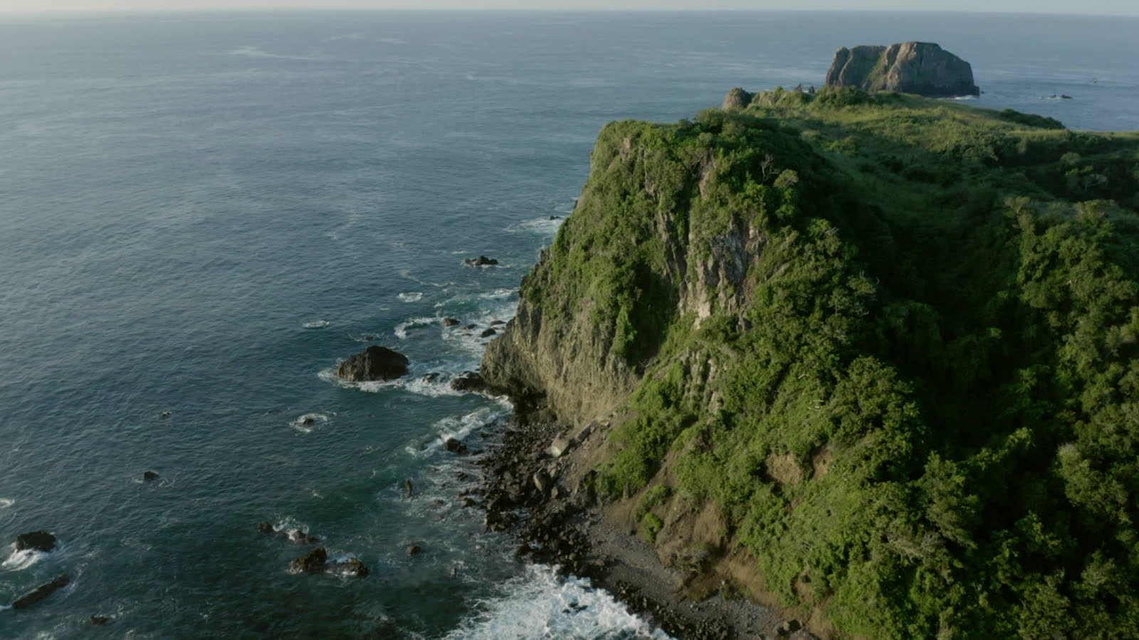 The headland from the water, cliffs falling to the sea