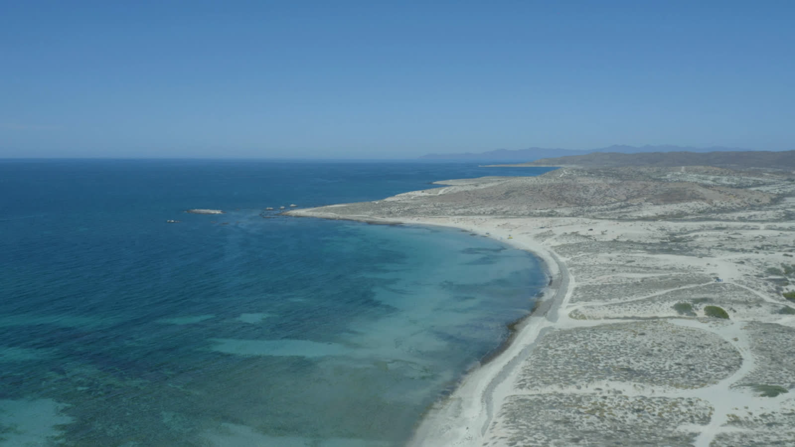 The bay's white shore curving below the site